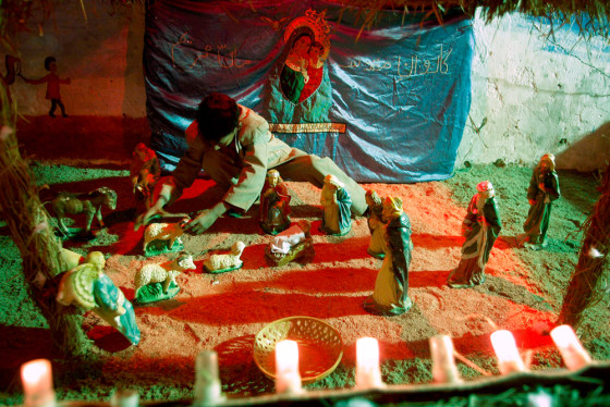 Image: A child arranges statues to celebarte Christmas