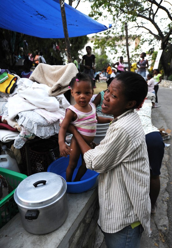 Image: woman bathes her daughter in a temporary camp