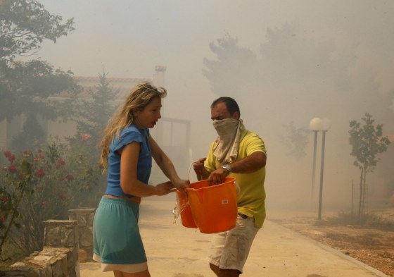 Image: People carry buckets of water as they try to put out a forest fire in Kapandriti village, a few miles northeast of Athens
