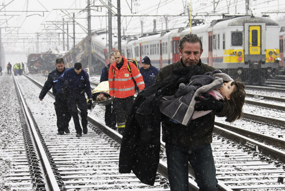 Image: A man carries a child from the site where two trains crashed near Halle, Belgium