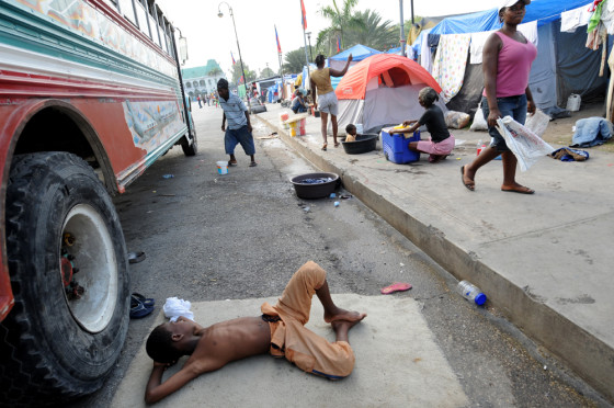Image: A Haitian boy rests next to a camp set up in front of the Presidential Palace in downtown Port-au-Prince