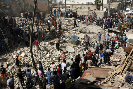 Image: Onlookers and resecue teams gather at the scene of a massive blast in central Baghdad