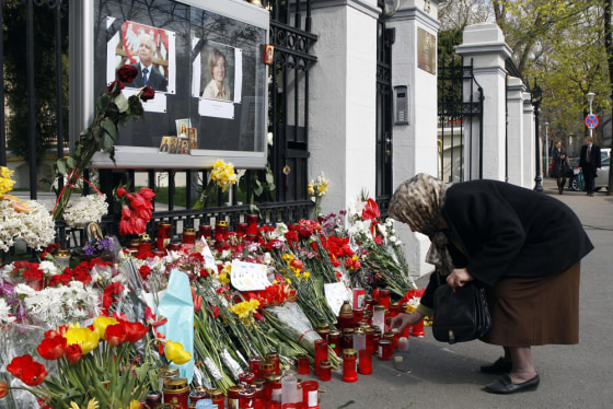 Image: A woman lights a candle in front of the Polish Embassy in Bucharest.