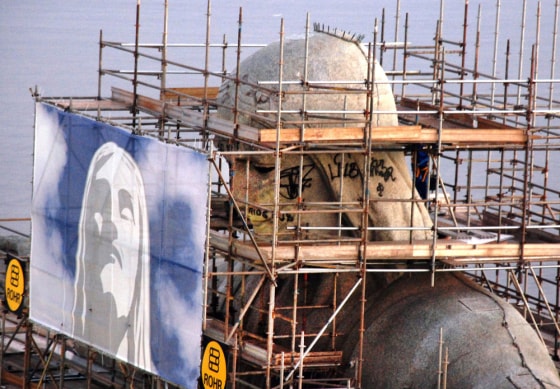 Image: the head of the Christ the Redeemer statue, graffitted with sentences about the violence and unsolved crimes