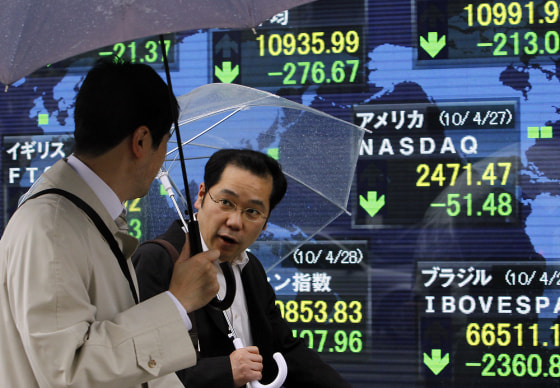 Image: People walk past an electronic stock indicator in Tokyo, Japan