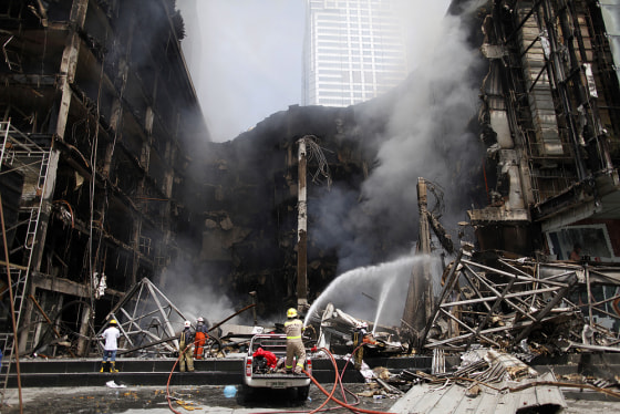 Image: Firemen try to extinguish fire at a shopping mall near anti-government \"red shirt\" protesters' abandoned stage in central Bangkok