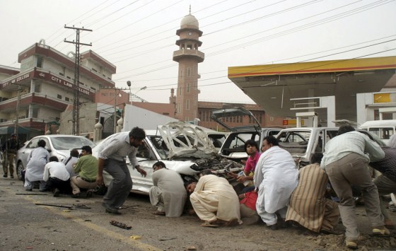 Pakistani media take cover outside one of two mosques stormed by gunmen in Lahore on Friday. Gunmen dressed in suicide vests attacked two mosques belonging to a minority sect, killing scores.
