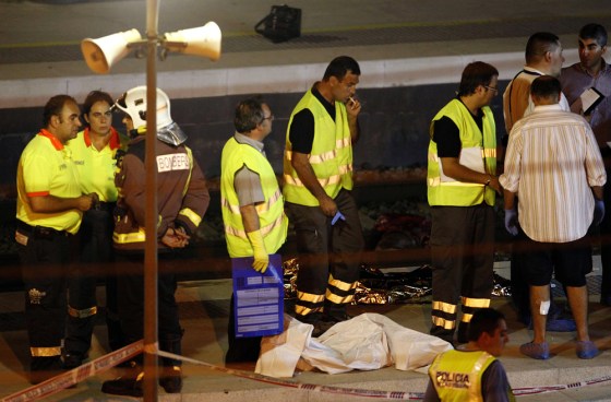 Image: Police collect the bodies of crash victims at train station near Barcelona