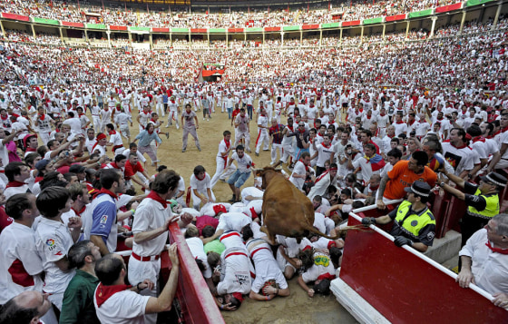 Image: A young bull jumps over a group of 'mozos,' or bull runners