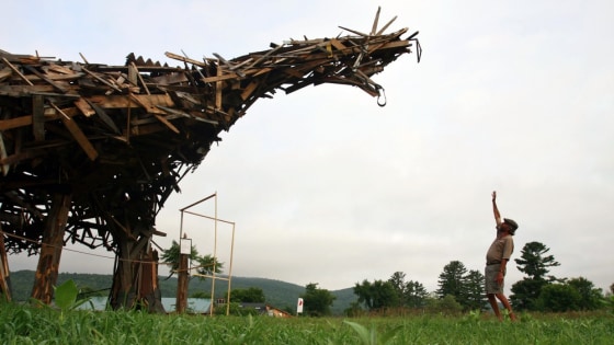 Image: In this photo taken Friday, July 9, 2010, Brian Boland, 61, a former teacher, hot-air balloon designer and balloon pilot who runs the rural Post Mills Airport in Thetford, Vt., stands with his \"Vermontasaurus\"