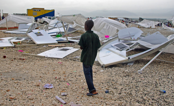Image: A boy walks in front of a structure that collapsed due to heavy rain at the Corail refugee camp