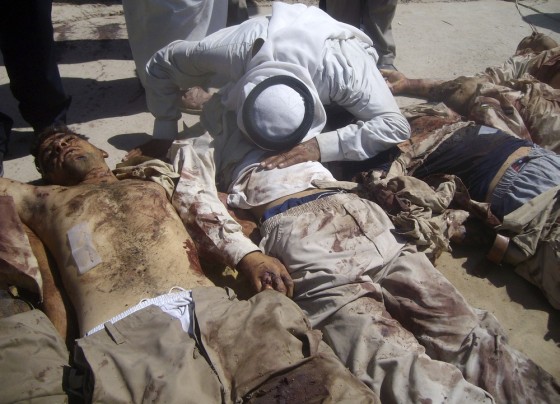 Image: A resident kisses the body of a government-backed Sunni militia member laid on the ground of a hospital yard in the town of Mahmudiya