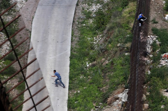 Image: Two men illegally cross the border fence separating Nogales, Ariz., and Nogales, Sonora, Mexico