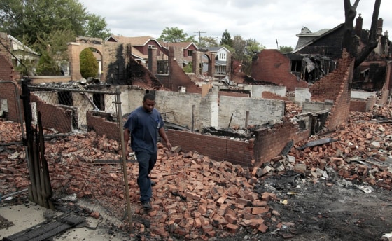 Image: A Detroit fire fighter looks through the smoldering back yards of burned homes and garages on East Robinwood in Detroit, Michigan
