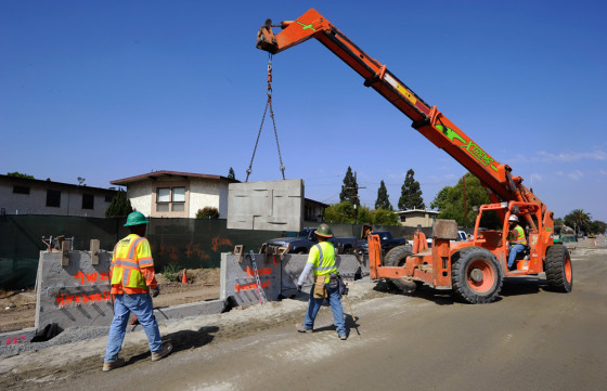 Image: Construction workers move a piece of concrete wall