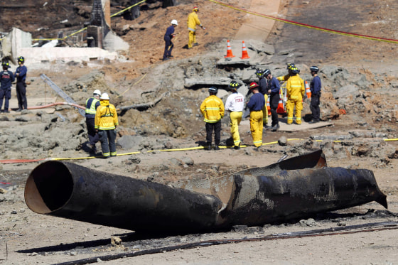 A wrecked gas pipe lies on street as investigators gather at the scene of a natural gas explosion in San Bruno