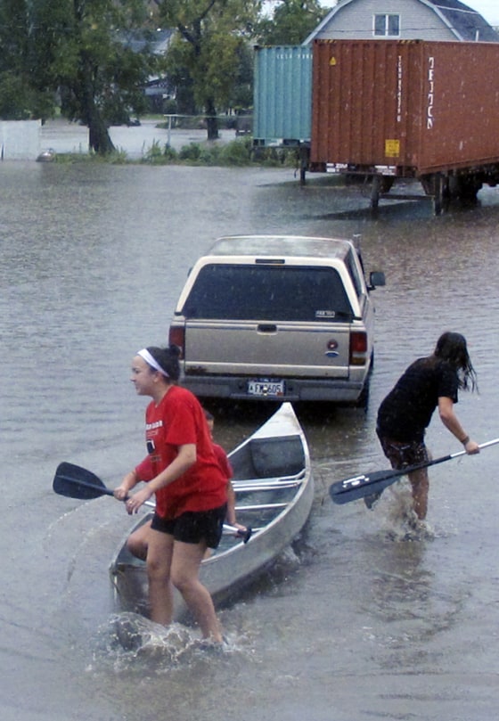 Image: Olivia Leavitt and Kenzie Kubis, canoe through the flooded streets of Arcadia, Wis.