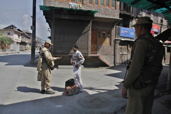 Image: An Indian paramilitary soldier checks the identity card of a civilian