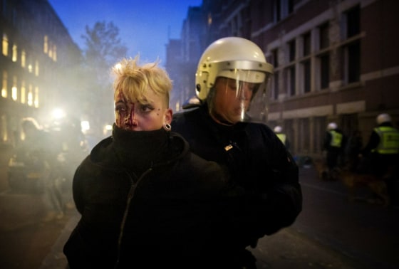 Image: A police man detains a female demonstra