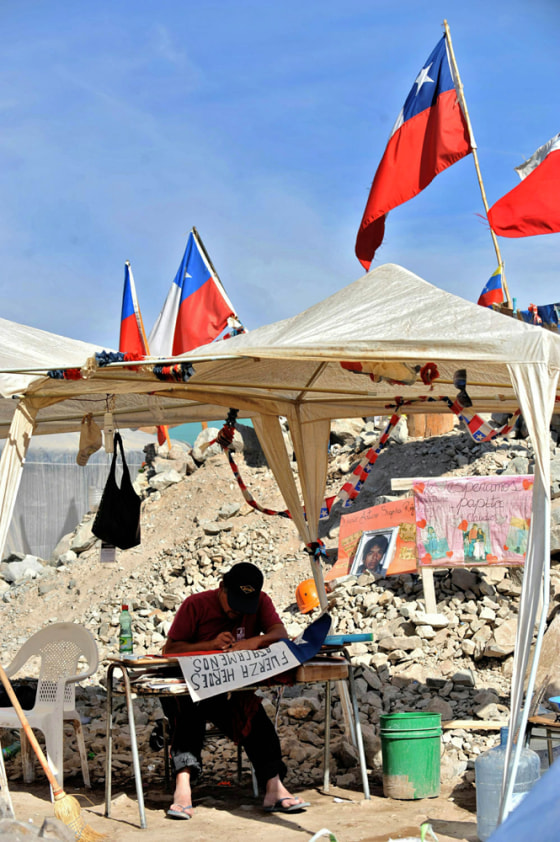 Image: A relative of one of the 33 miners trapped in San Jose mine writes a message on a Chilean national flag.