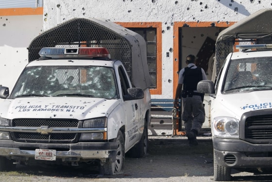 Image: A policeman walks among bullet-riddled patrol trucks after an attack at a police station in the town of Los Ramones