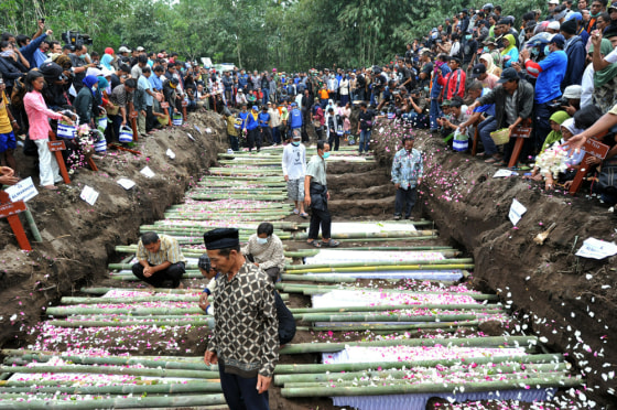 Image: Relatives sprinkle flower petals over the coffins of the victims of the Mount Merapi eruption during a mass funeral in Sidorejo
