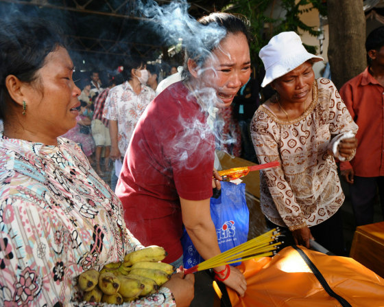 Image: Women cry as they prepare to carry home the body of their loved one among victims of the stampede placed in a makeshift morgue inside the Calmette hospital