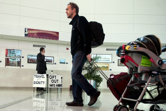 Image: A lone protester from Campaign For Liberty, Jonathan Scheaffer (L), stands at a table with Opt Out information as travelers head to thier gates
