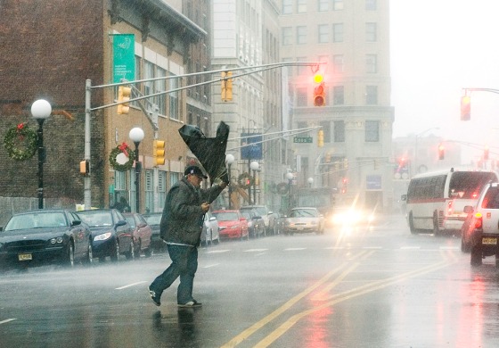 Image: A man's umbrella flips from the strong wind as he crosses Sip Avenue in Jersey City, N.J.