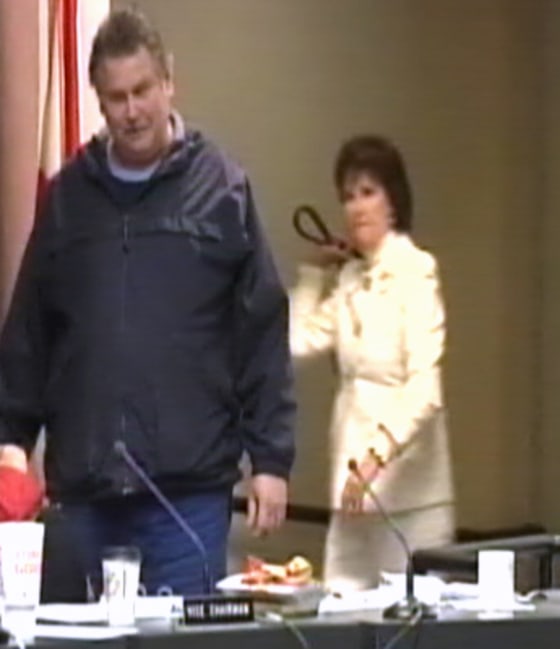 Ginger Littleton, right, attempts to disarm Clay Duke with her purse during a school board meeting.