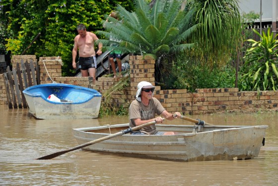 Image: Residents use boats to travel down the rroad after the swollen Fitzroy River broke its banks and flooded the city of Rockhampton