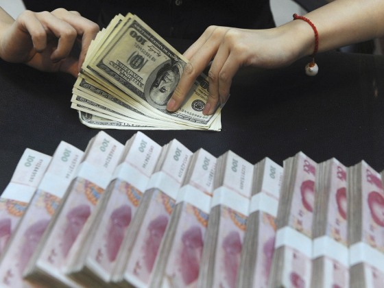 Image: File photo of an employee counting U.S. dollars next to yuan banknotes at a bank in Hefei
