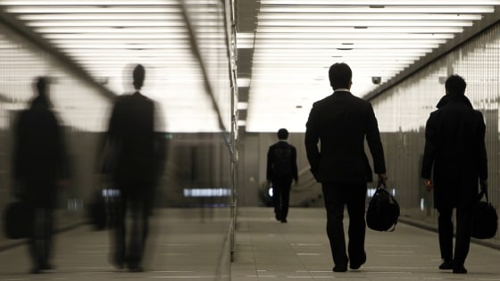 Image: Businessmen walk through a business complex in Tokyo