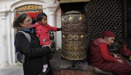 Celia Bergman holds Karina, as she tries to spin a prayer wheel during a visit to the Boudhanath Buddhist stupa in Katmandu, Nepal. Bergman and her husband, Chad, say they've decided to sell their condominium in Chicago to help defray the high costs of persisting with efforts to adopt the 3-year-old girl after the U.S. suspended adoptions.
