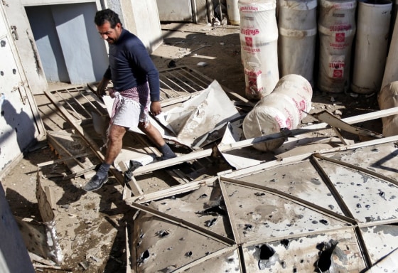 Image: A man walks through rubble at the site of a car bomb attack in Baghdad