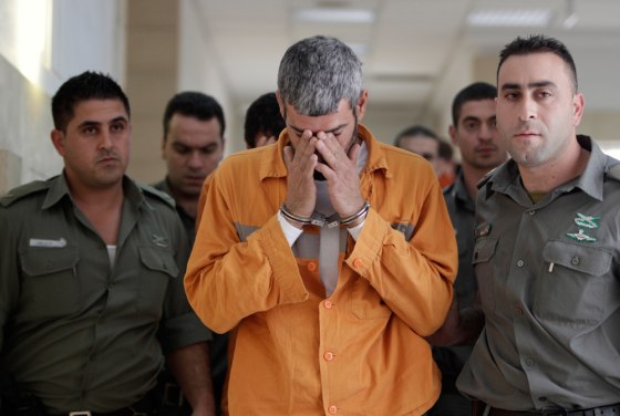 Image: A man charged with murder and attempted killing is escorted by Israeli prison guards in Jerusalem District Court