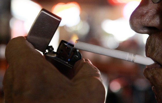 Image: A man lights a cigarette