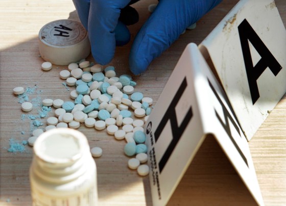 Image: a Franklin County police officer counts pills containing pseudoephedrine during a raid of a suspected meth house in Gerald, Mo.