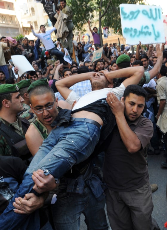 Image: man is carried away after he was injured by accident during pushing as Syrian workers protest to show support for their regime in front of the Syrian embassy in Beirut, Lebanon