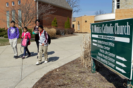 Image: Heather Coffy, right center, leaves the St. Monica School with her children in Indianapolis