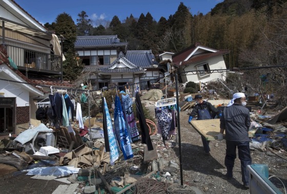 Image: The laundry of residents of Oshima island dry on a line as they carry Japanese tatami mats trying to clean their tsunami-damaged home in northeastern Japan