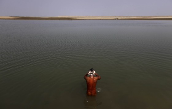 Image: A villager bathes in a tributary of the Brahmaputra river