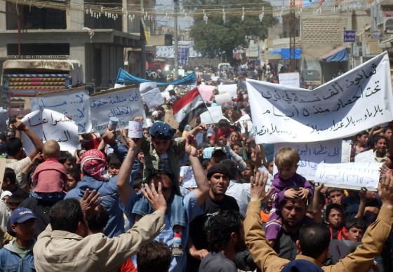 Image: Syrian anti-government protesters hold banners calling for an end to a military siege in Nawa near the southern town of Daraa on April 28.