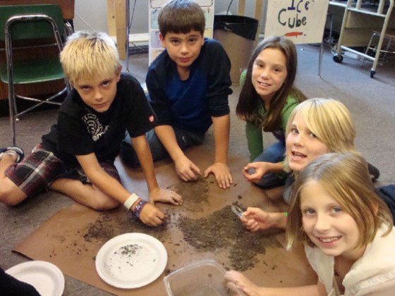 Fourth-grade scientists in action, sifting through dirt from a mastodon excavation.
