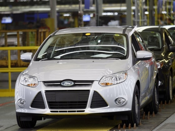Image: A Ford Motor assembly worker watches new 2012 Ford Focus vehicles move along the final production line at Michigan Assembly Plant in Wayne