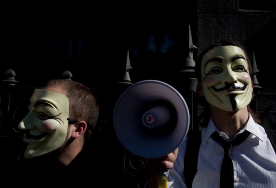 Image: People wearing masks often used by a group that calls itself \"Anonymous\" take part in a rally in Madrid
