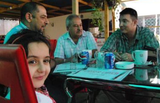 Captain Tom Hickey, right, speaks with Mohammad Adnan with his daughter Sadeel at the table. A colleague of Captain Hickey is between them. Hickey helped save Sadeel's life in 2007 when his soldiers rushed her to hospital after she was shot in the Baghdad neighborhood of Amariyah.