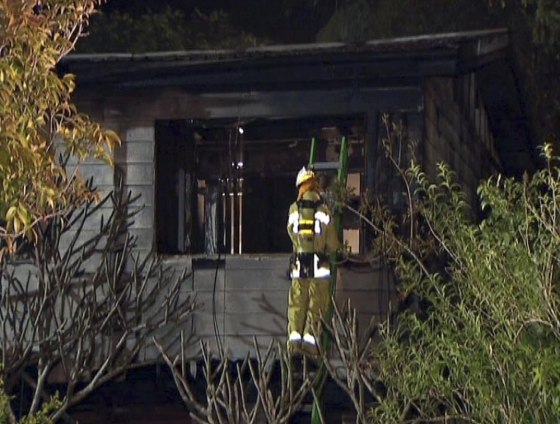 Image: A fire fighter inspects a house destroyed by fire in the northern Australian city of Brisbane