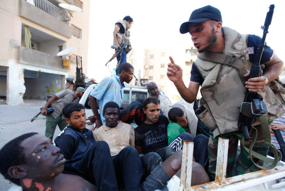 Image: Libyan rebel fighters stand guard over detainees during a fight for the final push to flush out Muammar Gaddafi's forces in Abu Salim district in Tripoli