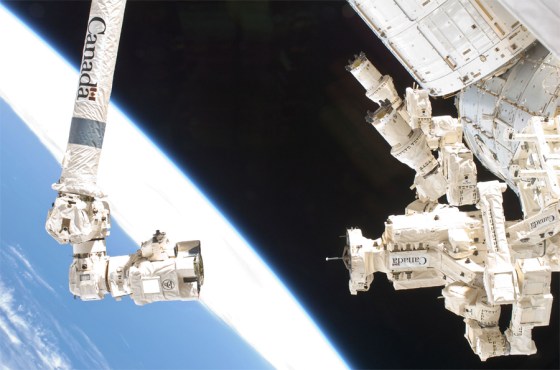 The International Space Station's two-armed robot Dextre is visible on right next to the Canadarm 2 robotic arm.